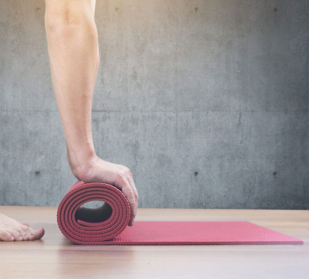 person rolling a yoga mat